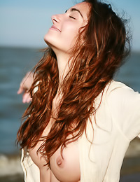 Redhead teen gal Gabrielle B walks down the beach naked and touches her firm big milk cans.