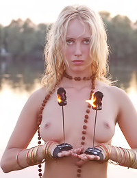 Smoking hot blonde vixen Astarta A takes off her lingerie and then dances around the fire.